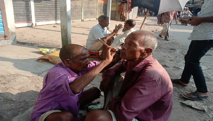 হারিয়ে যাচ্ছে মাটিতে বসে চুল দাড়ি ছাঁটা